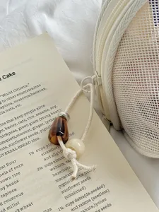 Detailansicht der beigen Mesh Kosmetiktasche mit stilvollem Perlen Zipper Anhänger.