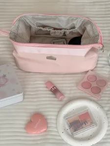 Grosse kosmetiktasche in rosa mit reisverschluss offnung und gestreiftem innenfutter.