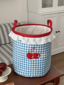 Detailansicht des blauen Karo-Aufbewahrungskorbs mit süßer Kirschenstickerei und Rand.