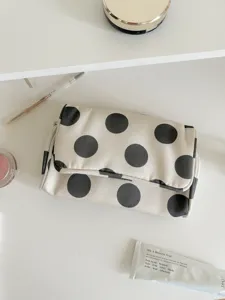Close-up detail of the black and white polka dot canvas makeup bag for travel storage.