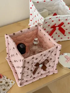 Quilted fabric storage basket with cute polka dots and bow, perfect for desktop organization.