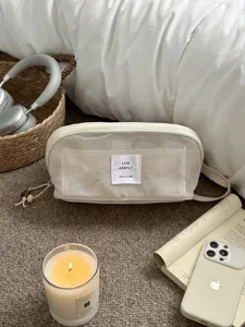 Cremefarbene Netz Kosmetiktasche Detailansicht mit Reissverschluss und Stofflabel für Reisen.