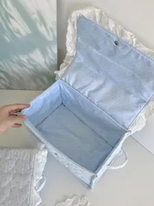 Fabric storage basket detail showing soft blue polka dot interior and white lace trim.