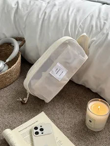 Detailaufnahme einer Kosmetiktasche aus beigem Mesh mit grossem Fassungsvermögen für Reisen.