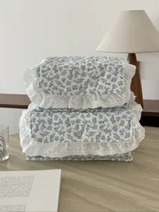 Detailansicht des blau geblümten gesteppten Aufbewahrungskorbs mit Spitze und Druckknopf, Tisch.