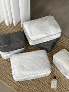 Travel packing organizers set for suitcase, grid pattern and solid white storage bags for clothes.