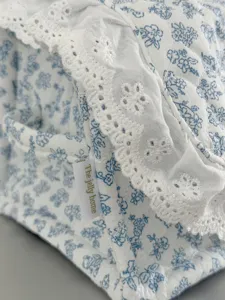 Detailansicht des blau-weißen Stoff-Aufbewahrungskorbs mit filigranem Spitzenbesatz.