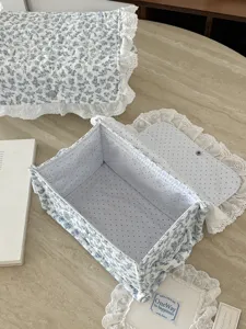 Blauer Blumen-Stoffaufbewahrungskorb mit Spitzenbesatz und Pünktchen-Innenfutter für den Tisch.