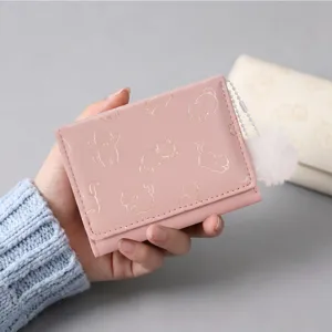 Detailansicht des süßen rosa kurzen Klappgeldbörsen mit goldenen Katzenmustern und Bommel.