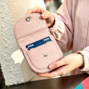 Close-up detail of women's pink leather fold wallet with card slots and metal snap closure.