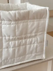 Witte gewatteerde opbergmand met elegante borduurdetails voor bureau-organisatie.