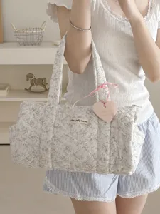 Dettaglio borsa tote cilindrica floreale trapuntata con texture e etichetta a cuore.
