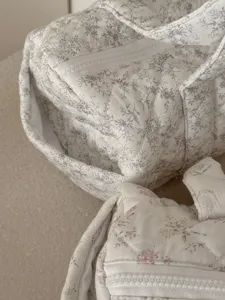 Primo piano dettagliato di una borsa cosmetica cilindrica floreale trapuntata con zip liscia.