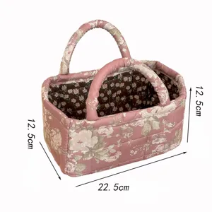 Quilted fabric storage basket in floral pink with double handles for desktop sundries organization.