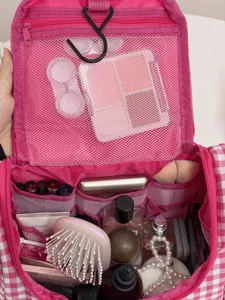 Gedetailleerd uitzicht op het roze-witte geruite cosmetische tasje met vele vakken.