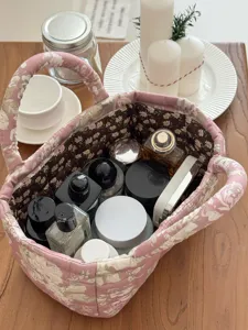 Detailed shot of quilted fabric storage basket with floral pattern and handles on wooden table.