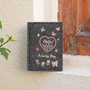 Close-up of dark denim trifold wallet featuring exquisite embroidered flowers and cute butterflies.