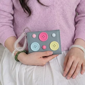 Close-up of cute dopamine color button wallet with spring wristlet, trendy minimalist design.