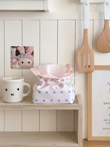 Detail shot of a cute pink and blue polka dot fabric tissue box on a wooden shelf.