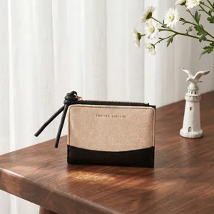 Detailed view of short two-fold women wallet with beige canvas and black leather trim.