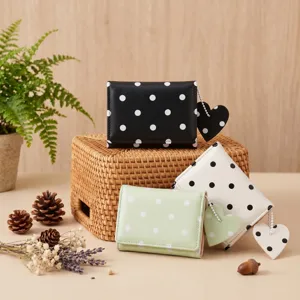 Primo piano di piccoli portafogli a pois chic con graziosi ciondoli a cuore e design minimalista.