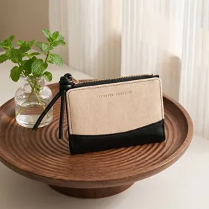 Detail view of the two-tone canvas and leather wallet with wristlet zipper pull in styled scene.