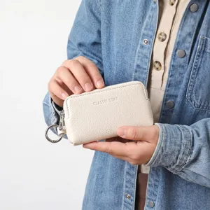 Pochette à clés compacte en cuir texturé avec fermeture éclair et anneau beige.