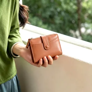 Detail shot of brown leather women fold wallet with card slots and zipper pocket.