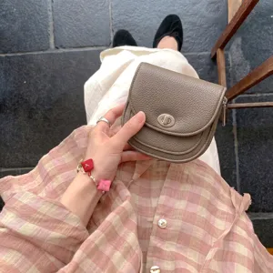 Detailed view of women's taupe leather small saddle coin purse with metal turn-lock closure.