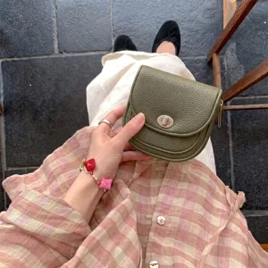 Olive green textured leather mini saddle bag detail showing metal turn lock and chic style.