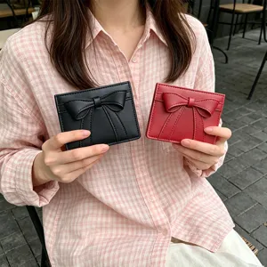 Close-up detail of cute bow design card holder wallet in hand, portable mini purse style.
