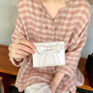 Close-up detail of a cute white card holder with an elegant bow design for women.