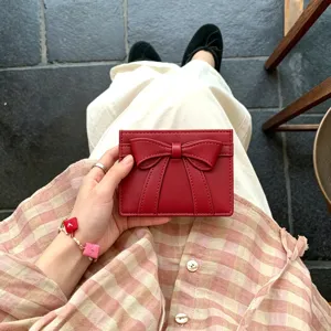Detail view of a cute red cardholder featuring a 3d bow design, compact wallet for women.