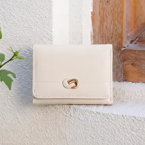 Detail shot of the minimalist tri-fold wallet showing textured leather and gold clasp.
