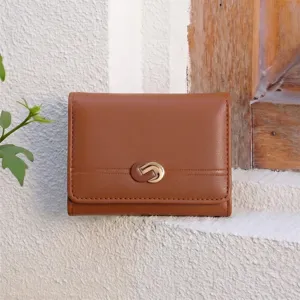 Detailed shot of brown tri-fold wallet with elegant metal buckle against rustic wall.