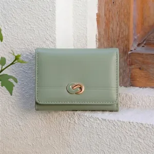 Close-up detail of a minimalist light green trifold women wallet with chic metal clasp on texture.