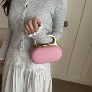 Pink acrylic evening clutch bag close-up detail shot, featuring a stylish gold metal handle.