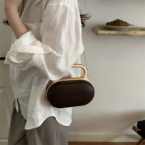 Detailed view of dark brown oval clutch bag with golden metal handle and chic chain strap.