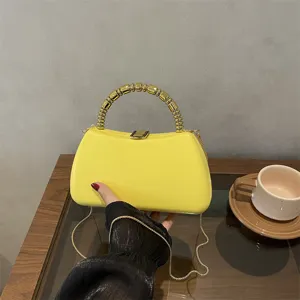 Detail view of yellow PU hard box evening clutch bag with unique gold beaded handle and chain.