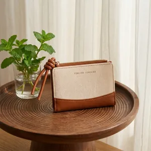 Canvas bi-fold wallet with brown leather trim and knotted strap, compact coin purse detail.