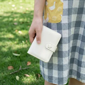 Vue détaillée du carnet à anneaux en cuir vernis blanc brillant avec un fermoir étoile.