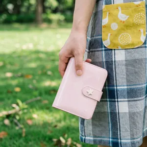 Gros plan détaillé du joli carnet à anneaux en cuir vernis rose avec un bouton étoile.