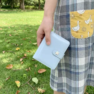 Gros plan sur un agenda à anneaux en cuir vernis bleu clair avec fermoir étoile en plein air.