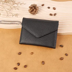 Close-up of a black litchi pattern mini wallet with chain, elegant envelope design, detail view.