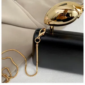 Elegante zwarte avondtas voor dames met gouden bloemknop handvat en fijne ketting.