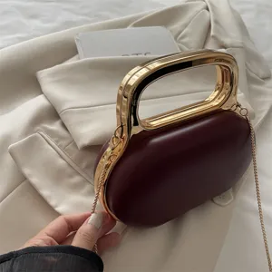 Burgundy oval evening bag featuring a gold metal rigid handle and chic chain strap detail.
