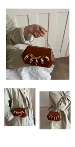 Detailansicht der stylischen Acryl-Clutch Tasche mit Goldkette und einzigartigem Klauendesign.