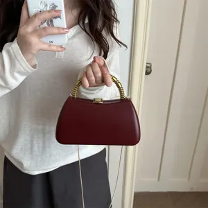 Detailed view of the dark red hard-shell evening clutch with gold metal handle and chain.