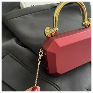 Exquisite red acrylic box evening bag with gold metal handle and chain strap detail.
