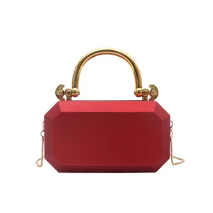 Close-up of the red acrylic box evening bag featuring a gold metal handle and delicate chain strap.